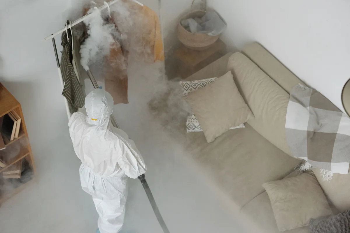 Technicien équipé traitant une pièce de vie contre les punaises de lit
